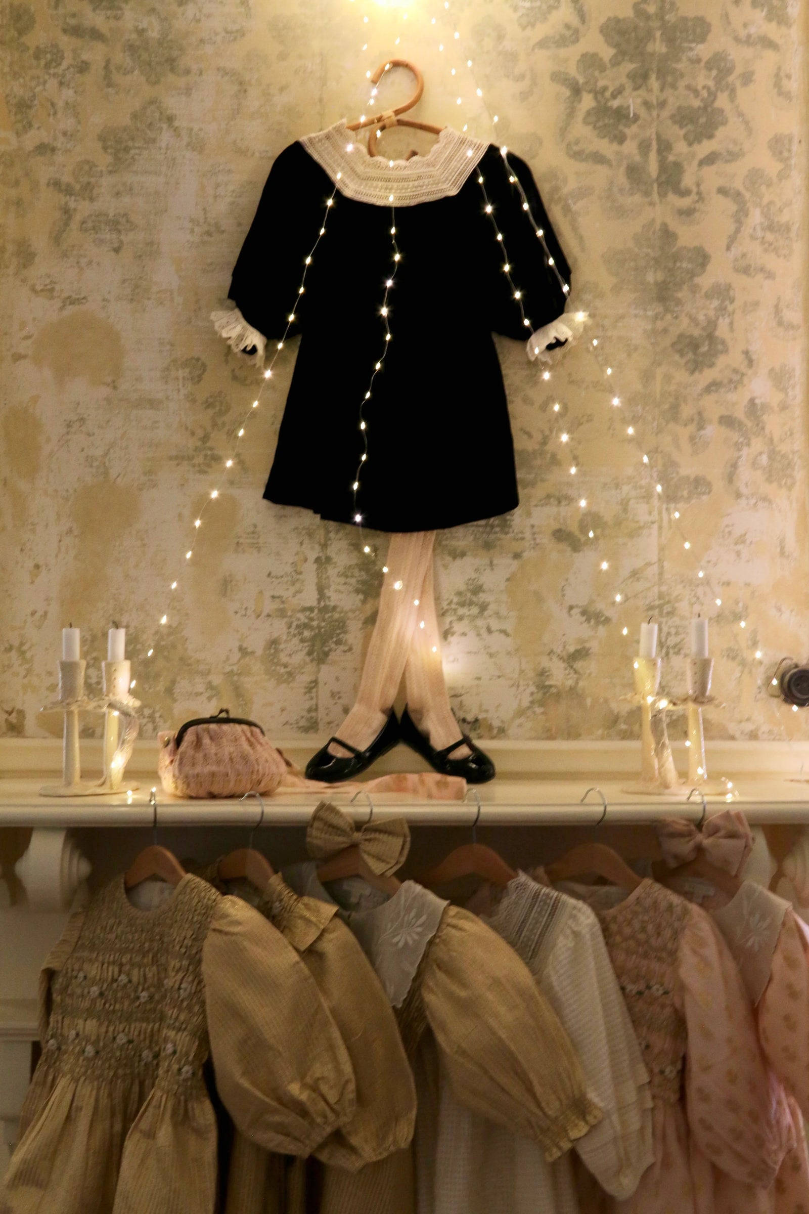 Vintage-inspired childrenswear display with fairy lights and delicate dresses on hangers