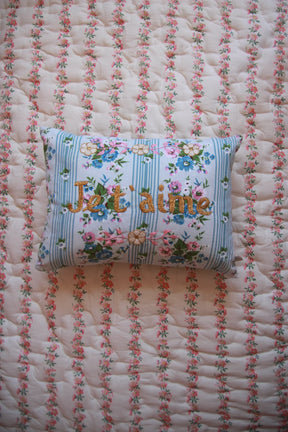 Floral embroidered cushion with 'I love you' on a quilted floral bedspread