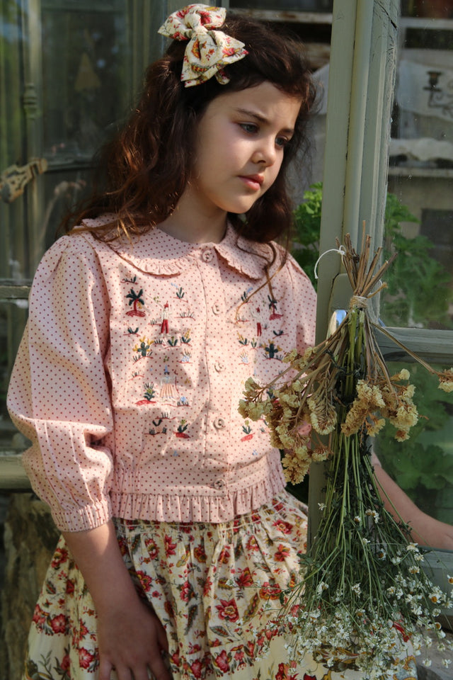 Embroidered blouse with small red polka dots on a pink background