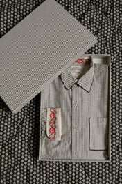 Striped cotton shirt with floral cuff detail in gift box on patterned fabric background