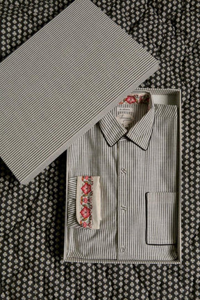 Striped cotton shirt with floral cuff detail in gift box on patterned fabric background