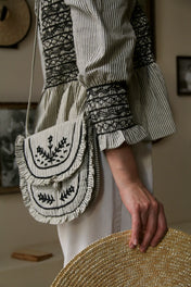 Striped cotton bag with black embroidered floral design, worn over a matching blouse sleeve.