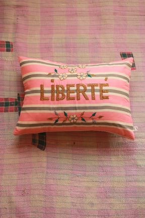 Pink and cream striped decorative pillow with embroidered flowers and 'LIBERTÉ' on pink quilt