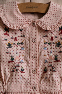 Embroidered blouse with small red polka dots on a pink background