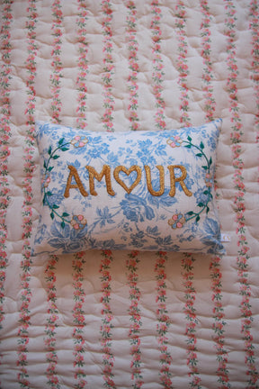 Embroidered floral cushion with 'AMOUR' text on a pink and white floral quilt