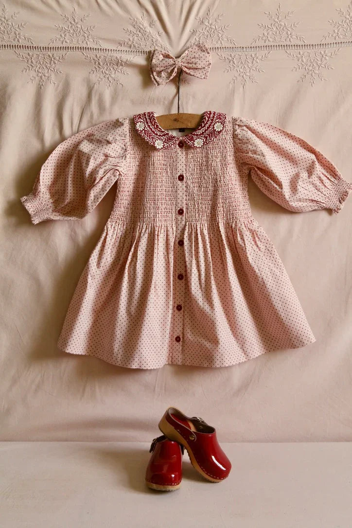 Red polka dot tunic on a pink background with matching hair clip