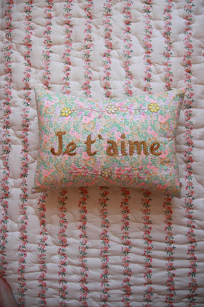 Floral embroidered pillow with "I love you" text on a quilted floral bedspread