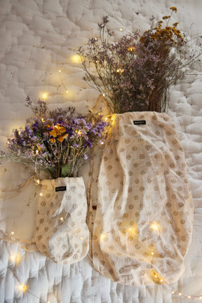 Two floral print cotton pouches with dried flowers and fairy lights on a quilted blanket